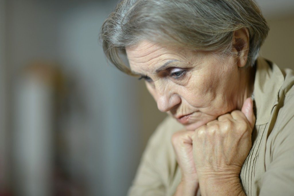 upset elder with her chin above her closed hands