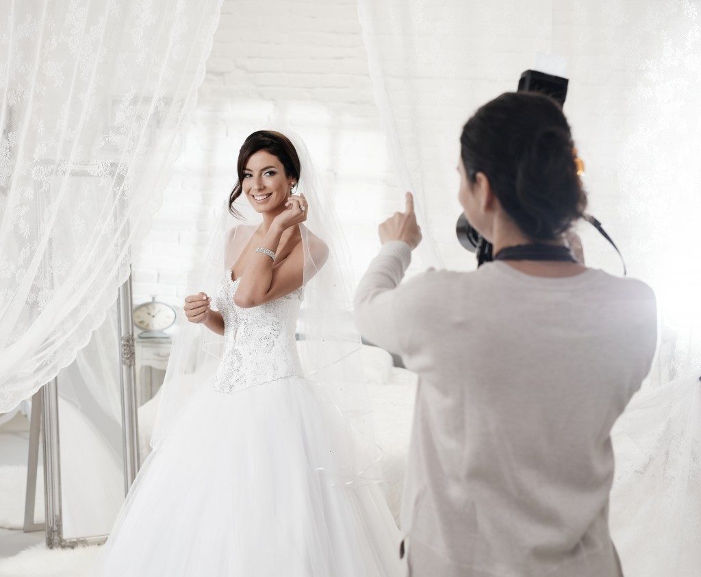 Female photographer taking pictures of bride